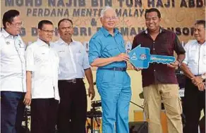  ?? PIC BY FARIZUL
HAFIZ AWANG ?? Prime Minister Datuk Seri Najib Razak handing over a mock key to a recipient of the Tekek Makmur People’s Housing Project in Pulau Tioman yesterday. With him are Pahang Menteri Besar Datuk Seri Adnan Yaakob (second from left) and Urban Wellbeing,...