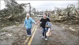  ?? JOHN SPINK — ATLANTA JOURNAL-CONSTITUTI­ON ?? Two women make their way down a debris filled street in Coweta County, Ga., on Friday after a tornado moved through the area.