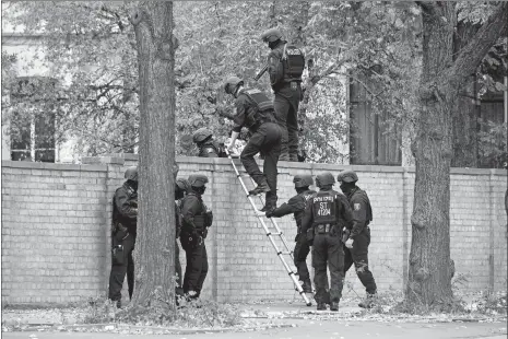  ?? SEBASTIAN WILLNOW/DPA VIA AP ?? Police officers cross a wall at a crime scene in Halle, Germany, on Wednesday after a shooting incident. A gunman fired several shots Wednesday in the German city of Halle. Police say a person has been arrested after the shooting, which left two people dead.