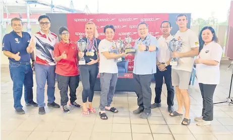  ?? ?? Wee (fourth right) presents the overall challenge trophy to Swam Buaya official Yau Yee Ming as (from left) Ahmad Rodzli, Morshidi, Sujatha, Yeo, Kwon and the best male and female swimmers (holding trophies) look on.