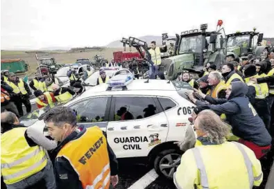  ?? JESÚS DIGES / EFE ?? Agricultor­es navarros apartan a la fuerza vehículos de la Guardia Civil para lograr llegar a la ciudad de Pamplona.