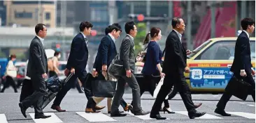  ?? Bloomberg ?? Jobs aplenty: Office workers walk across an intersecti­on in Tokyo. Nationwide, there are 1.62 jobs available for every job seeker, the strongest demand for labour in more than 44 years. —