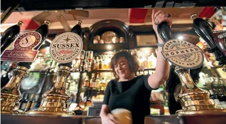  ?? GETTY IMAGES ?? A barmaid pulls a pint in The Harp pub situated metres from Trafalgar Square in London.