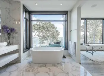  ?? PHOTOS: JOSHUA LAWRENCE STUDIOS ?? The ensuite offers views of Oak Bay, screened by Garry oaks. Two-by-three-foot tiles have a white background and tracings of dark grey that complement the sculptural trees outside.