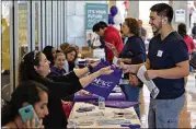  ?? DAULTON VENGLAR/AMERICAN-STATESMAN ?? Angelica Diaz-Miranda De La Rosa hands an Austin Community College bag to a visitor at an ACC Highland campus career fair.