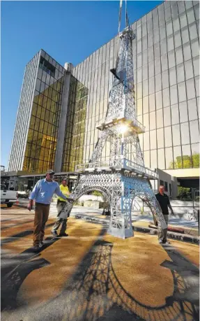  ?? STAFF PHOTO BY TIM BARBER ?? Outside the new Westin hotel in Chattanoog­a, Kevin Fairchild, left, and his crew move a 25-foot-tall replica of the Eiffel Tower down Pine Street on its way to its resting location. The constructi­on of the tower was performed by Engineered Mechanic...