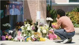  ?? ASHLEY LANDIS/AP ?? Gabe Kipers kneels at a memorial for his neighbor Dr. John Cheng outside Cheng’s office building Tuesday in Aliso Viejo, Calif. Cheng, 52, was killed Sunday.