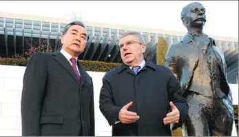  ?? PENG DAWEI / FOR CHINA DAILY ?? IOC President Thomas Bach introduces the Olympic Museum to Foreign Minister Wang Yi in Lausanne, Switzerlan­d, on Sunday, beside a statue of Pierre de Coubertin, founder of the modern Olympics.