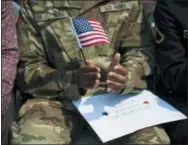  ?? JOE LAMBERTI — CAMDEN COURIER-POST VIA AP ?? Olivier Duverneau claps with his American flag after becoming a citizen during a naturaliza­tion ceremony aboard the USS New Jersey, Wednesday in Camden, N.J.