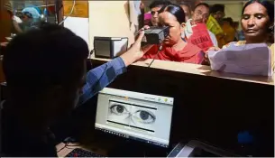  ?? — AFP ?? Hi-tech security: A woman looking through an optical biometric reader that scans a person’s iris patterns as part of the Aadhaar registrati­on process in Amritsar.