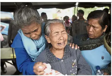  ?? — AFP ?? Hard to accept: Relatives of victims of the sunken ferry being overcome by a sense of hopelessne­ss as they wait at Tigaras port in Lake Toba.