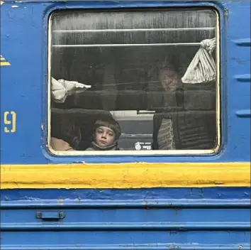  ?? ?? A Ukrainian family looks out from the window of a train taking them to a safer part of the wartorn country.