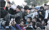  ?? GIANNIS PAPANIKOS / THE ASSOCIATED PRESS ?? Migrants hold their documents as they wait to cross the Greek-Macedonian border near the village of Idomeni.