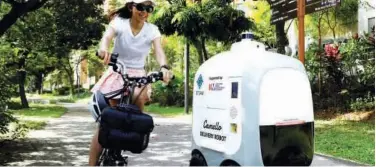  ?? File / Reuters ?? ↑
A cyclist passes as Camello, an autonomous grocery delivery robot, makes its way during a delivery in Singapore.