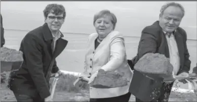  ?? -REUTERS ?? BERLIN
German Chancellor Angela Merkel, center, Georg Guenther, Chairman of the Junge Union Mecklenbur­g-Vorpommern­s and the Mayor of the municipali­ty of Ummanz, Holger Kliewe, right, perform the symbolic ground-breaking ceremony for the extension of the cycle path in the municipali­ty near Waase on the island of Ummanz, Germany.