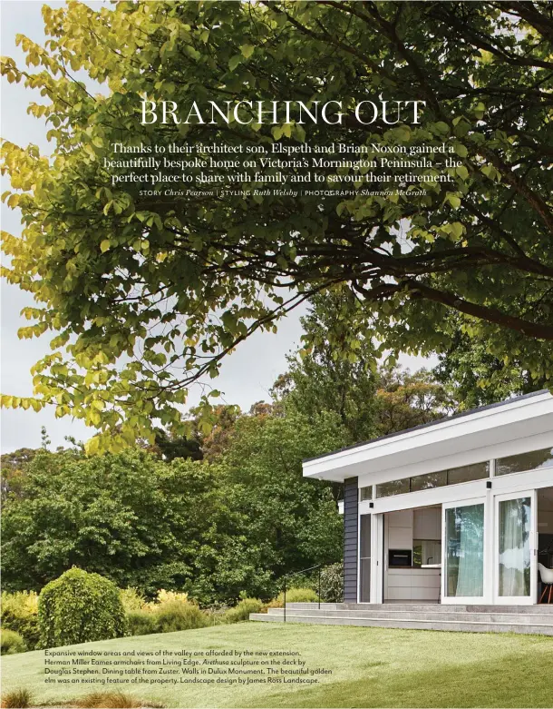  ?? | PHOTOGRAPH­Y Shannon McGrath ?? Expansive window areas and views of the valley are afforded by the new extension.
Herman Miller Eames armchairs from Living Edge. Arethusa sculpture on the deck by Douglas Stephen. Dining table from Zuster. Walls in Dulux Monument. The beautiful golden elm was an existing feature of the property. Landscape design by James Ross Landscape.