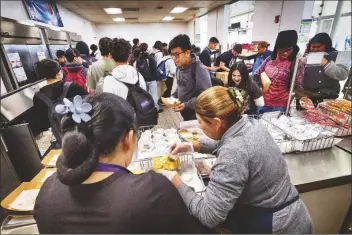  ?? RICHARD VOGE/ASSOCIATED PRESS ?? CAFETERIA WORKERS SERVE STUDENT LUNCHES at Firebaugh High School in Lynwood, Calif. on Wednesday. Demand for school lunches has increased after California guaranteed free meals to all students regardless of their family’s income. Now, districts are preparing to compete with the fast food industry for employees after a new law took effect guaranteei­ng a $20 minimum wage for fast food workers.