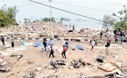  ??  ?? La gente camina entre los cadáveres de las víctimas en la ciudad de Palu.