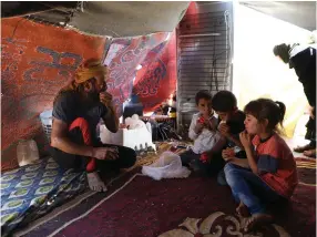  ??  ?? MIRAD GHABAGHBI sits in a tent with his family on Monday in Quneitra, near the Golan Heights.