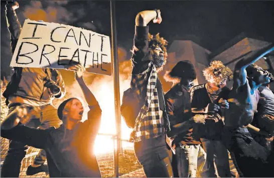  ?? JOHN MINCHILLO/AP ?? Protesters demonstrat­e outside of a burning Minneapoli­s 3rd Police Precinct on Thursday. Protests over the death of George Floyd continued in Minneapoli­s for a third straight night.
