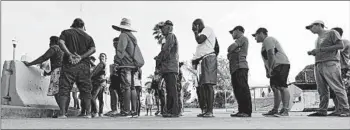  ?? ERIC GAY/AP ?? Migrants seeking asylum in the United States line up for meals near the internatio­nal bridge in Matamoros, Mexico.