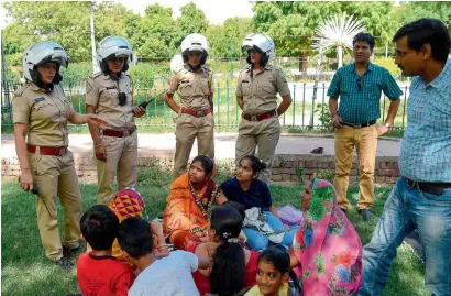  ?? AFP ?? Members of the female patrol unit explain to women and children about the women’s helpline numbers in a park in Jaipur. —