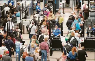  ?? David Zalubowski / Associated Press ?? Travelers move through the north security checkpoint in the main terminal of Denver Internatio­nal Airport on Thursday. Hundreds of flights worldwide were canceled by mid-afternoon Sunday.