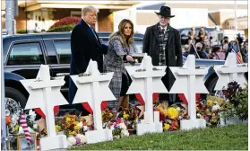  ??  ?? Flanked by President Donald Trump and Rabbi Jeffery Myers, first lady Melania Trump lays a flower at the memorial Tuesday outside the Tree of Life synagogue in Pittsburgh.