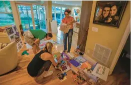  ?? TAMPA BAY TIMES ?? Members of the Boonstoppe­l family and a friend look through Harrison’s old drawings while they create a display in his memory at the Boonstoppe­ls’ Tampa home on Monday.