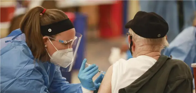  ?? NICOLAUS CZARNECKI PHOTOS / HERALD STAFF ?? ‘TURNING ON THE FAUCET’: People roll up their sleeves to receive their first dose of the COVID-19 vaccine at the Curative mass vaccinatio­n site at the DoubleTree by Hilton Hotel in Danvers on Wednesday.