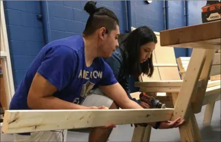  ?? RICHARD PAYERCHIN — THE MORNING JOURNAL ?? Lorain High School scholars Jason Chavez, a junior, and Noelia Mendoza, a freshman, take a break from studying climate control systems to assemble one of 16 benches for the Lorain Better Block event scheduled for May 19, on Broadway in Lorain.