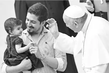  ??  ?? Pope Francis greets a child during a weekly general audience at the Paul VI audience hall in Vatican. — AFP photo