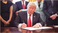  ?? (Carlos Barria/Reuters) ?? US PRESIDENT Donald Trump, accompanie­d by small-business leaders, signs an executive order cutting regulation­s at the White House in Washington on Monday.