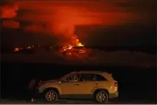  ?? GREGORY BULL — THE ASSOCIATED PRESS FILE ?? A man talks on a phone in his car alongside Saddle Road as the Mauna Loa volcano erupts Nov. 30 near Hilo, Hawaii.