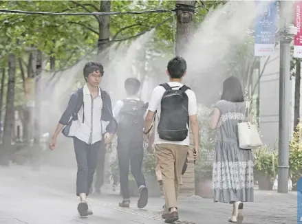  ??  ?? People cool off under water sprays at Chiyoda-Ku in Tokyo, Japan, on August 3, 2018.