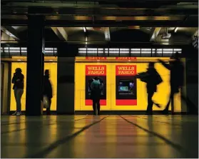  ?? SAM HODGSON / THE NEW YORK TIMES ?? People visit Wells Fargo ATMS April 7 in the Port Authority subway station in New York. The Federal Reserve gave a passing grade to Wells Fargo and all 34 of the institutio­ns it checks annually for financial soundness — the first all clear since the...