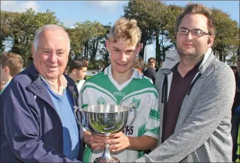  ??  ?? Joe Kelly receives the cup from Noel O’Keeffe (Coiste na nOg) and Dean Goodison (People Newspapers).