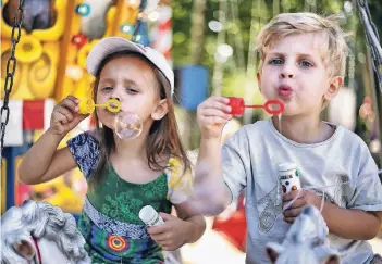  ??  ?? Jule (3) und Levio (3) haben Spaß beim Seifenblas­en auf dem Karussell. Das Wetter spielte beim großen Kinderfest in Metzkausen mit.