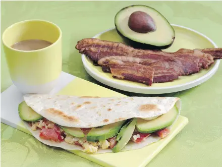  ?? — THE ASSOCIATED PRESS ?? Avocado, onions and tomatoes are added to eggs to make breakfast tacos. Bacon stays crispier if it’s on the side, but it can be chopped and added to the taco.