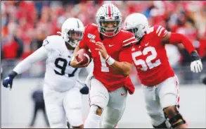  ?? The Associated Press ?? TAKING THE LEAD: Ohio State quarterbac­k Justin Fields, center, runs for a first down against Penn State during the first half of Saturday’s game in Columbus, Ohio.