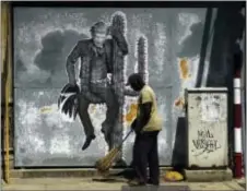  ?? RAMON ESPINOSA - THE ASSOCIATED PRESS ?? A street sweeper cleans the sidewalk under a mural painting depicting U.S. President Donald Trump, in Havana, Cuba, Friday. President Trump is en route to Miami, where he’ll announce his plans for halting the flow of U.S. cash to Cuba’s military and...