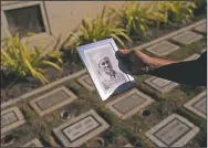  ?? (AP/Jae C. Hong) ?? Holding a photo of his grandfathe­r, Giichi Matsumura, Clyde Matsumura pauses while visiting his father’s grave after a memorial service for his grandfathe­r.