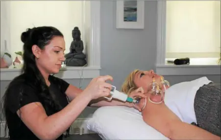  ?? PHOTOS BY MICHILEA PATTERSON — FOR DIGITAL FIRST MEDIA ?? Licensed massage therapist Lindsey Crits uses a tension relief method called “cupping” on her client Patti Coates at the Center Massage studio in Royersford. Plastic cups and a pump suction the skin in order to loosen stiff muscles.