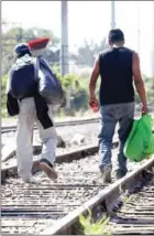  ?? ULISES RUIZ/AFP ?? Central American migrants walk along the railroad tracks as they wait to board a train known as ‘The Beast’ to reach the border with the US, in Jalisco state, Mexico, on Tuesday.