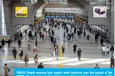  ??  ?? TOKYO: People wearing face masks amid concerns over the spread of the COVID-19 coronaviru­s walk in Shinagawa station in Tokyo yesterday. —AFP