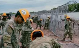  ?? CHENEY ORR/NEW YORK TIMES ?? Members of the National Guard installed temporary fencing topped with razor wire near Eagle Pass, Texas, last week.