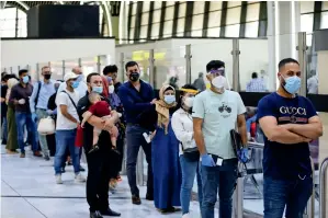  ?? Reuters ?? WAITING IN QUEUE: Passengers wearing protective masks queue for check-in at the departure hall after the reopening of Baghdad Internatio­nal Airport in Baghdad, Iraq, on Thursday. —