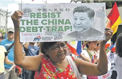  ??  ?? Una manifestan­te filipina levanta una pancarta con un retrato del dictador chino Xi Jinping durante una protesta frente a la oficina consular china en Manila contra la creciente influencia de la superpoten­cia asiática.