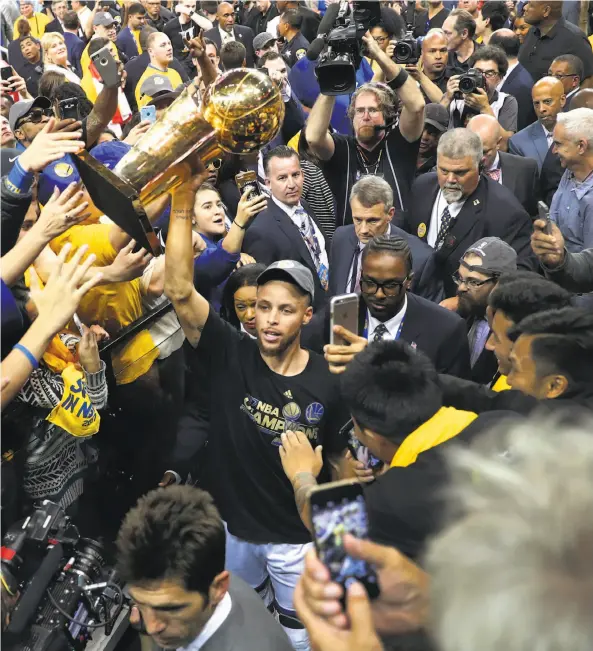  ?? Scott Strazzante / The Chronicle ?? Above: Stephen Curry carries the Lawrence O’Brien Trophy off the court after the Warriors defeated the Cleveland Cavaliers to earn the NBA title.