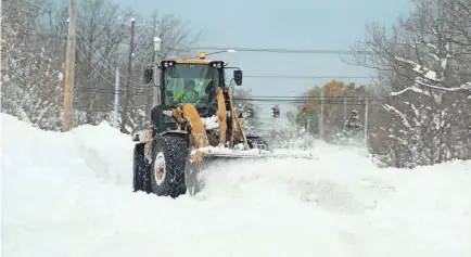  ?? JOHN NORMILE/GETTY IMAGES ?? A National Guard loader clears a road on Saturday, after an intense lake-effect snowstorm hit the area.